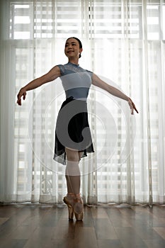 Young graceful ballet dancer in tights and leotard practicing new movement for performance