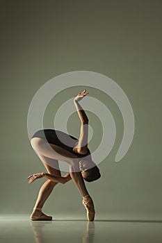 Young graceful female ballet dancer dancing in mixed light