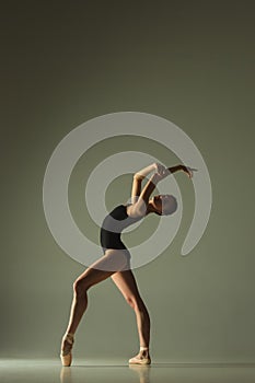 Young graceful female ballet dancer dancing in mixed light