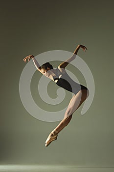 Young graceful female ballet dancer dancing in mixed light