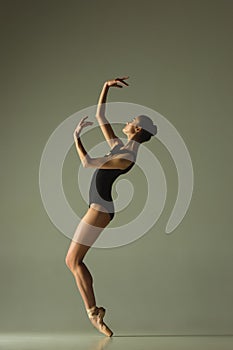 Young graceful female ballet dancer dancing in mixed light