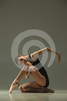 Young graceful female ballet dancer dancing in mixed light