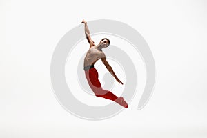 Young graceful male ballet dancer dancing on white studio background