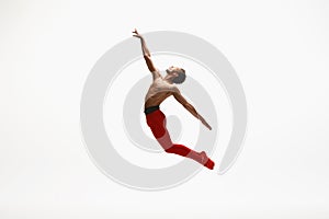 Young graceful male ballet dancer dancing on white studio background