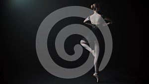 Young graceful woman ballerina in black dress doing a pirouette