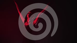 Young graceful woman ballerina in black dress slowly dancing in red lighting