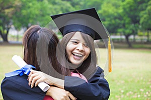 Young graduate hugging her friend at graduation ceremony