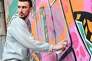 A young graffiti artist looks around while drawing. Vandal tries