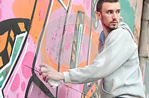 A young graffiti artist looks around while drawing. Vandal tries