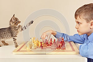 Young grandmaster with kitten plays chess.