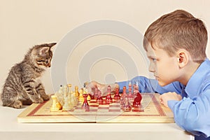 Young grandmaster with pretty kitten plays chess.