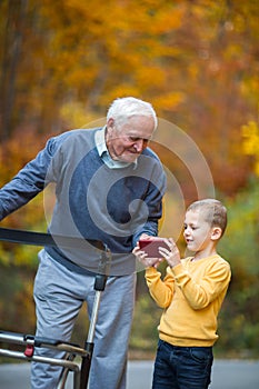 Young grandson showing something on phone to grandfather
