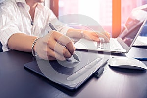 Young graphic designer man using digital tablet and computer laptop on black table at home office