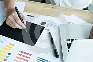 Young graphic designer working with computer and color swatch. c
