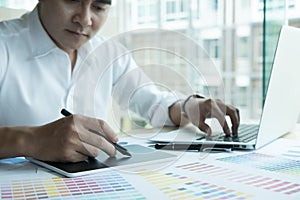 Young graphic designer working with computer and color swatch. c