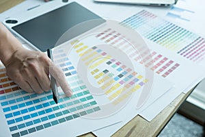 Young graphic designer working with computer and color swatch. c
