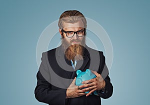 Young greedy stingy business man holding piggy bank photo