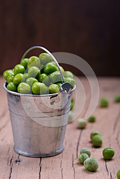 Young green peas in a small bucket on the tableTasty and healthy food