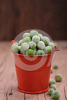 Young green peas in a small bucket on the tableTasty and healthy food