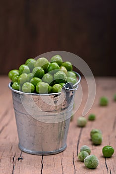 Young green peas in a small bucket on the tableTasty and healthy food