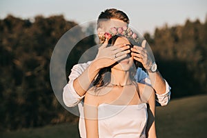 young groom closing eyes to beautiful smiling bride