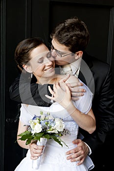 Young groom cuddle beautiful bride and kissing her.