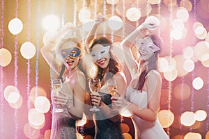 Young group celebrating New Year and drinking champagne on masquerade party