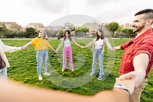 Young group of diverse friends in circle holding hands in a park