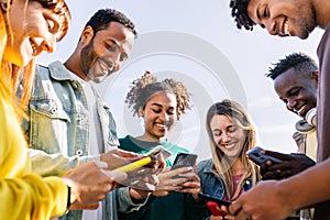 Young group of happy friends using smart mobile phone together outdoors