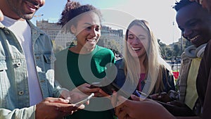 Young group of happy friends using smart mobile phone together outdoors