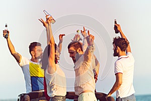 Young group having fun on the beach and dancing in a convertible car