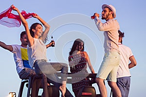 Young group having fun on the beach and dancing in a convertible car