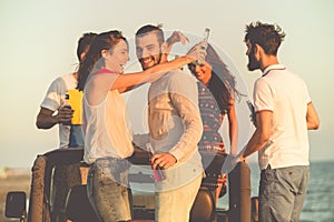 Young group having fun on the beach and dancing in a convertible car