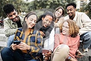 Young group of multiracial student friends using mobile phone in the city