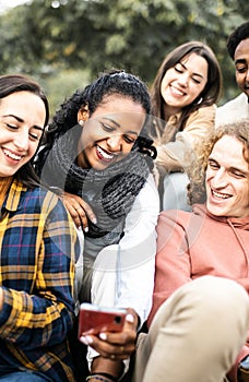 Young group of multiracial student friends using mobile phone in the city