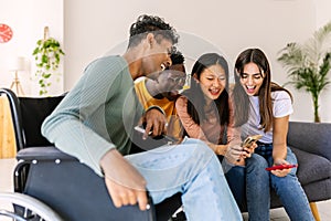 Young group of people using mobile phone device sitting together on sofa at home