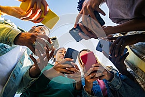 Young group of people using mobile phone device standing in circle outdoors