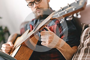 Young guitarist hipster at home with guitar fix capo