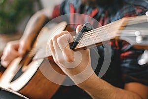 Young guitarist hipster at home with guitar holding capo