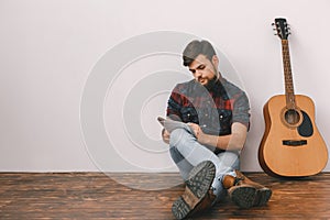 Young guitarist hipster at home with guitar sitting writing melody