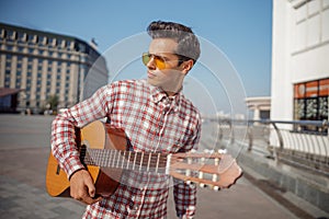 Young guitarist looking away on the street