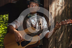 Young guitarist plays acoustic guitar on countryside