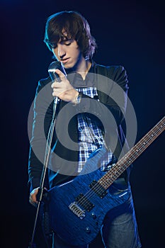 Young guitarist standing in smoke on stage