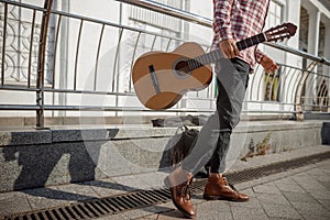 Young guitarist walking in the street with his instrument