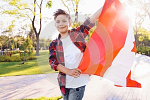 A young guy of 9 years old riding on a sunny road in the evening in the city park, dressed in a flannel plaid shirt. Holding