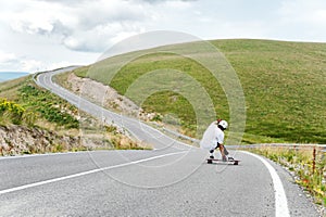 A young guy action makes a slide on a longboard in the resort area of the city