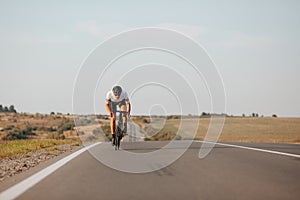 Young guy in activewear biking fast on paved road