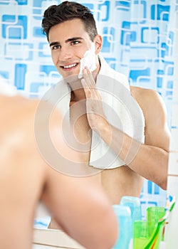 Young guy applying cream to his face for a shave