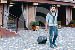 Young Guy Arab Businessman Student Came go to Restaurant With Suitcase in Hand, Smiling at Camera, Stops and Looks Away.