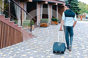 Young Guy Arab Businessman Student Came go to Restaurant With Suitcase in Hand, Smiling at Camera, Stops and Looks Away.